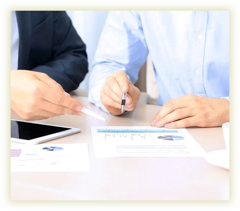 Two people sitting at a table with papers and pens.